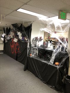 an office decorated for halloween with black and white decorations on the walls, tables covered in plastic