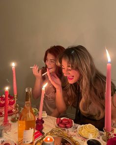 two women sitting at a table with food and candles