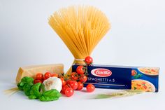 pasta, tomatoes, basil, garlic and other ingredients on a white background with a box of spaghetti