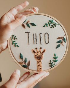 a person holding up a cross - stitch hoop with the word'tho'written on it