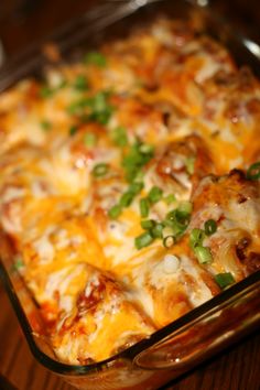 a casserole dish with cheese, green onions and meat in it on a wooden table