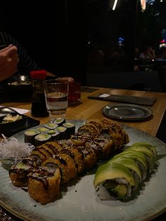 sushi rolls on a plate with avocado slices