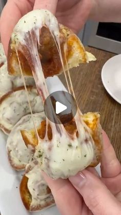 someone is holding up a pastry with cheese and sauce on it in front of other pastries