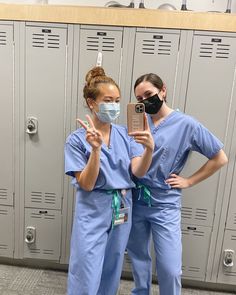 two nurses in scrubs are taking a selfie with their cell phone while wearing masks