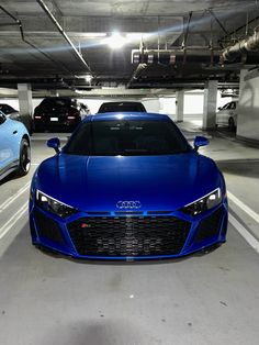 two blue sports cars parked in a parking garage