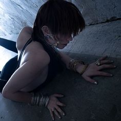 a woman laying on the ground with her hands in her pockets and wearing bracelets