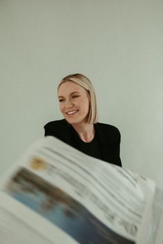 a woman is smiling while reading a newspaper