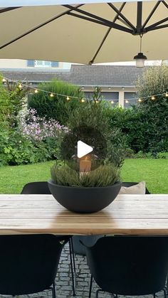 a table with chairs and an umbrella in the middle of a courtyard area that has plants on it