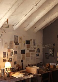 an office with lots of papers on the wall and a lamp hanging from the ceiling