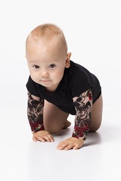 a baby crawling on the ground wearing a black shirt and leggings with red flowers