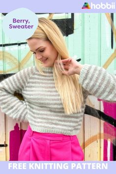 a woman with long blonde hair wearing a striped sweater and pink skirt, standing in front of a wall