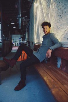 a young man sitting on top of a wooden bench