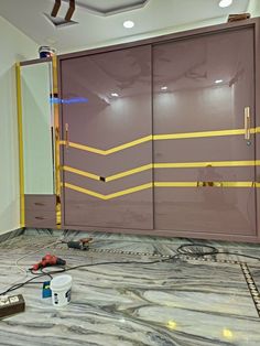 the interior of a room with some tools on the floor and cabinets painted purple, yellow and grey