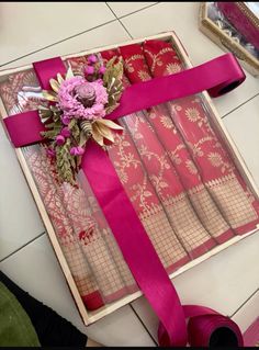 a box that has some flowers in it and ribbon on the inside of it,