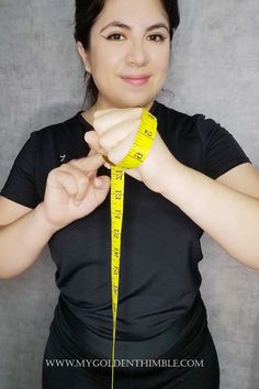 a woman is measuring her waist with a yellow tape around her neck and hands are holding the measure