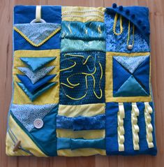 a blue and yellow patchwork quilt on a wooden floor with scissors, pins and thread