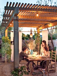 an outdoor dining area is lit up with candles and greenery on the table, surrounded by white curtains