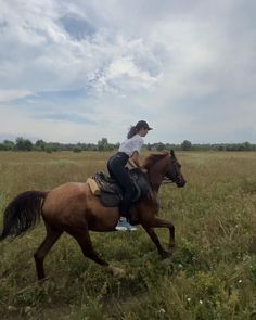 a woman riding on the back of a brown horse in a field with tall grass