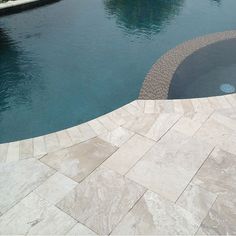 an empty swimming pool next to a stone patio