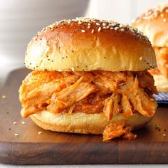 two pulled pork sandwiches with sesame seeds on a cutting board