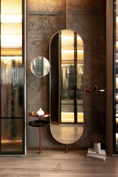 a large mirror sitting on top of a wooden floor next to a table with a vase