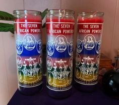 three candles sitting next to each other on top of a purple tablecloth covered counter