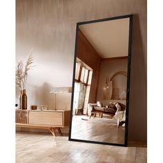 a large mirror sitting on top of a hard wood floor next to a wooden dresser