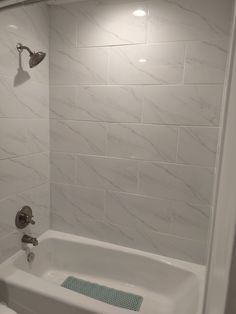 a white bath tub sitting inside of a bathroom next to a wall mounted shower head