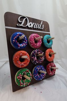 a wooden sign with donuts on it and sprinkles