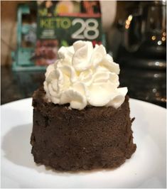 a piece of chocolate cake with whipped cream on top sits on a plate next to a book