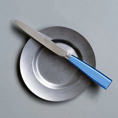 a blue handled knife sitting on top of a metal plate in the shape of a circle