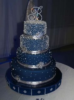 a three tiered blue wedding cake with silver decorations on the top and bottom layer