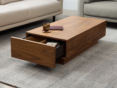 a coffee table with an open drawer on the bottom in front of a couch and rug