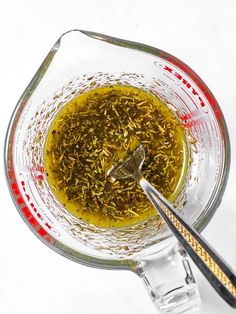 a glass bowl filled with green tea next to a spoon