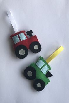 two handmade toys are sitting on a white surface, one is green and the other is red