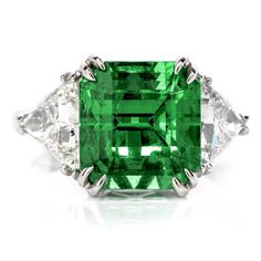 an emerald and diamond ring, with three diamonds on each side in white gold or silver