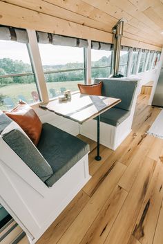 the interior of a mobile home with wood flooring and white walls, windows, and couches