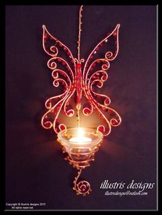 a candle that is lit up in the shape of a fairy wings hanging from a chain