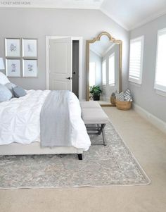 a large white bed sitting in a bedroom next to a window with shutters on it