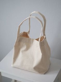 a canvas bag sitting on top of a white table next to a wall and chair