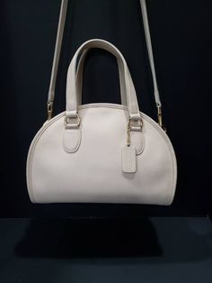 "For your consideration is this beautiful vintage Coach Chadwick Bag, or Bowler (style #9928) in Bone or ivory-white, with brass hardware. It is a \"Leatherware Era\" bag, and was made in the United Sates before 1994. It is in near Mint restored condition. I consider this bag to be the Grail of vintage Coach purses, and is one of the most beautiful bags that Coach made during this era. It is my favorite, and especially rare in bone. The Chadwick satchel is a unique Coach style that is sought aft Timeless Cream Satchel For Formal Use, Vintage Cream Bags With Detachable Handle, Vintage Cream Satchel For Travel, Vintage Beige Satchel With Top Carry Handle, Vintage Beige Satchel With Handles, Classic Cream Satchel With Top Handle, Vintage White Handheld Shoulder Bag, Vintage White Top Handle Shoulder Bag, Classic Cream Top Handle Satchel