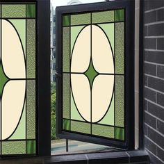 two stained glass windows in front of a brick wall with green and white designs on them