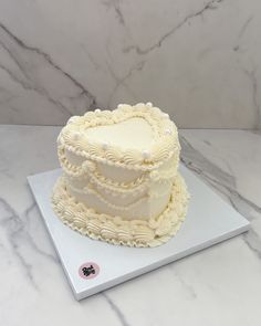 a white cake sitting on top of a table next to a marble countertop covered in frosting