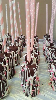 there are many chocolate covered straws with pink and white stripes on them, all lined up in rows