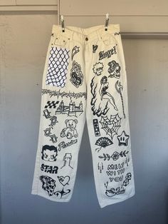 a pair of white pants with black and white drawings on them hanging from a clothes line