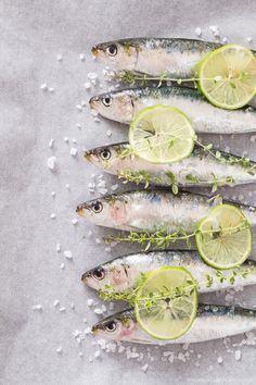 five fish with lemon slices and herbs on top of them next to salt and pepper