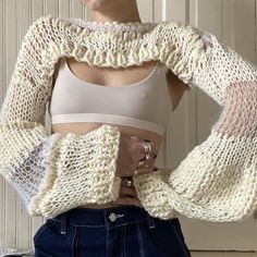 a woman with her hands on her hips wearing a crop top and knitted sweater