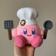 a crocheted toy with a chef hat and spatulas in it's hand