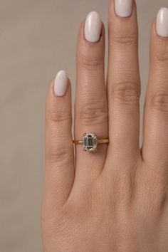 a woman's hand with a ring on it and a white manicured nail