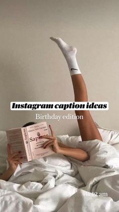 a woman laying in bed reading a book with her legs up on top of an open book